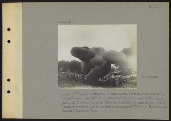 Ravin de Saint-Symphorien (Meuse). Ballon type M (Cacquot). Le ballon ramené à terre, maintenu par les équipes de manœuvre, on termine de le désarrimer. Ballon inventé par le capitaine Cacquot, en usage sur le front depuis juillet 1916. Il se caractérise par ses trois ballonnets stabilisateurs formant ailerons et fixes à l'arrière de l'enveloppe à gaz et se gonflant automatiquement à l'ascension. 26e compagnie d'aérostiers