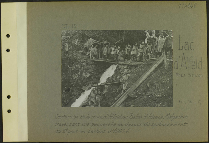 Lac d'Alfeld (Près Sewen). Construction de la route d'Alfeld au Ballon d'Alsace. Malgaches traversant une passerelle au-dessus du soubassement du deuxième pont en partant d'Alfeld