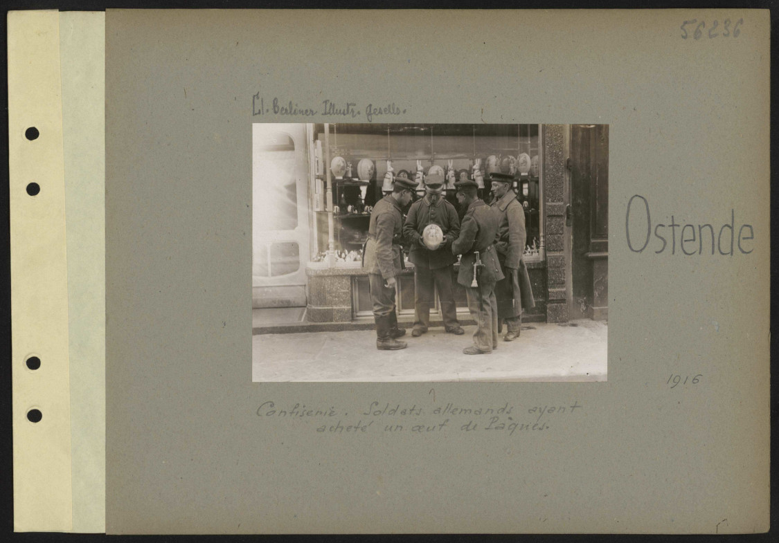 Photographie de soldats tenant un gros oeuf de Pâques devant la vitrine d'une confiserie