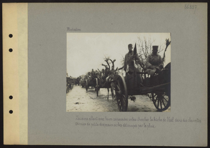 S.l. Zouaves allant avec leurs camarades serbes chercher la bûche de Noël dans des charettes garnies de petits drapeaux serbes détrempés par la pluie
