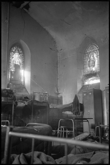 Photo de l'intérieur d'une église désaffectée utilisée comme logement d'urgence, avec des lits superposés