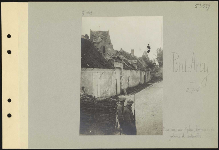 Pont-Arcy. Une rue ; au premier plan, barricade de gabions et sentinelles
