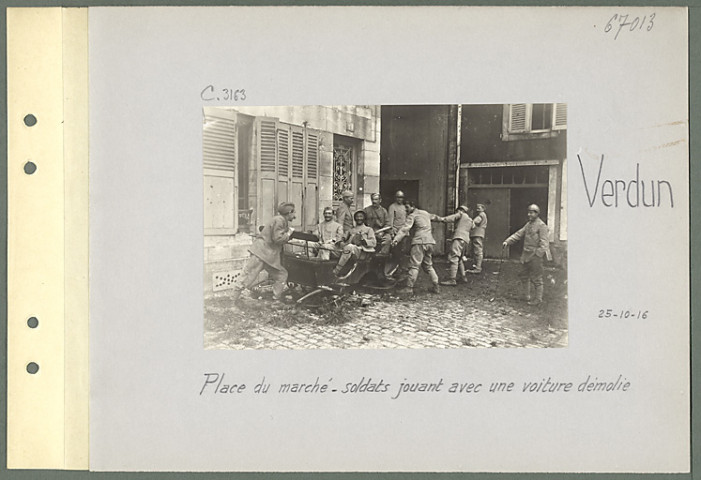 Verdun. Place du marché. Soldats jouant avec une voiture démolie