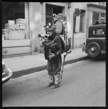 Photo d'un homme portant divers instruments de musique, dans une rue