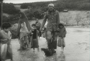Photo en noir et blanc montrant une famille de réfugiés marchant sur la route