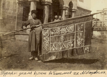 Photo d'un général portant un grand drapeau avec des inscriptions en alphabet arabe
