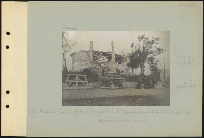 Souain. L'église bombardée : façade ouest. Au premier plan, la grosse cloche de l'église et, assis près de la cloche, un gendarme de service au carrefour des routes