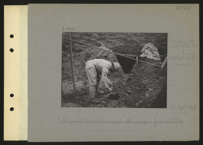 Domart-sur-la-Luce (près). Soldat versant de l'eau dans un casque allemand pour faire sa toilette
