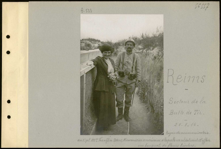 Reims (Secteur de la butte de Tir). Boyau de communication. Au premier plan madame Franklin Adam, d'une mission américaine, à laquelle un soldat vient d'offrir un bouquet de fleurs tricolore